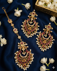 Ornate gold and red jewelry set with pearls on a dark blue fabric background.